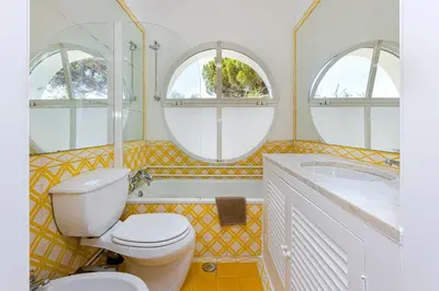 a bathroom with a toilet and a tub and two windows at Villa AL Fresco in Guia