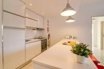 a kitchen with white cabinets and a white counter top at Modern Apartment by the Sea in Quarteira