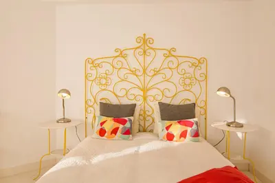 a bed with a gold headboard and two tables at Modern Apartment by the Sea in Quarteira
