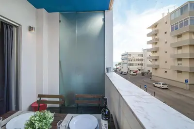 a balcony with a table and chairs and a street at Modern Apartment by the Sea in Quarteira