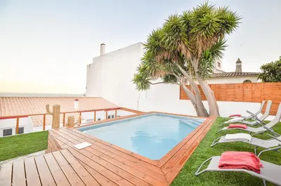 a swimming pool with chairs and a palm tree at Elevator's Beach House by Atlantic Places in Albufeira