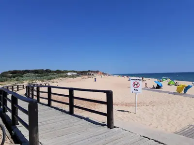 a wooden boardwalk on a beach with a no swimming sign at Alto do Forte Novo- Ar- Condicionado, Wifi, Vista Mar in Quarteira