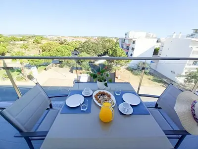 a blue table with a plate of food on a balcony at Alto do Forte Novo- Ar- Condicionado, Wifi, Vista Mar in Quarteira