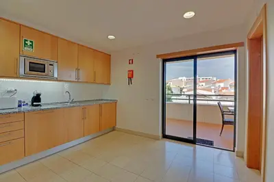 a kitchen with wooden cabinets and a view of a balcony at Albufeira Modern 1 with pool by Homing in Albufeira