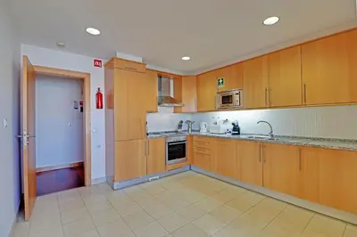 a kitchen with wooden cabinets and a sink at Albufeira Modern 1 with pool by Homing in Albufeira