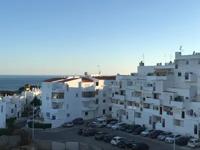 a large white building with cars parked in a parking lot at Apartament near the ocean in Albufeira