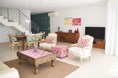 a living room with a tv and chairs and a table at Villas Rocha in Albufeira
