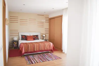 a bedroom with a bed with orange pillows and a rug at Villas Rocha in Albufeira