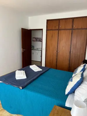 a bedroom with a large blue bed with wooden cabinets at Apartamento 806 in Albufeira