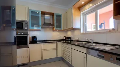 a kitchen with white cabinets and a sink and a window at Greice Homes-Luxury 2 bed en-suite south facing & Golf view in Quarteira