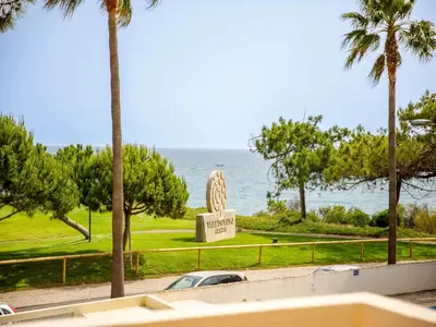 a statue in front of the ocean with palm trees at Villa Oceano Golf 482 2 Bedrooms Sea Views A Stone's Throw To The Beach in Vale do Lobo
