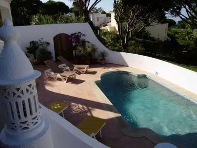 a swimming pool on a patio with chairs and a house at Vale Do Lobo Villa 4 Bedrooms Villa Vale Do Lobo 186 Swimming Pool in Vale do Lobo