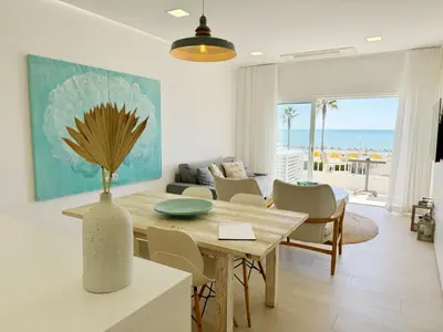a living room with a table and chairs and the ocean at Seafront Apartment in Quarteira in Quarteira