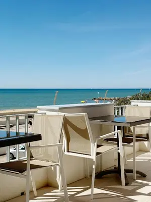 a table and chairs and a boat on the beach at Seafront Apartment in Quarteira in Quarteira