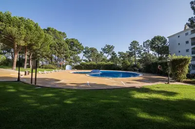 a swimming pool in a park with trees and grass at Falésia Pine Spot in Albufeira