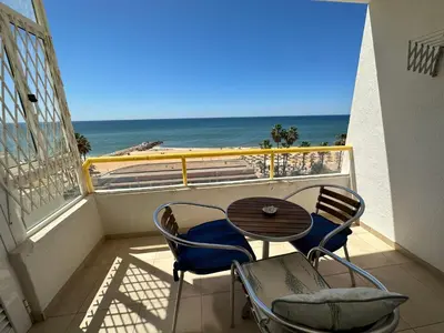 a balcony with a table and chairs and the ocean at Apartamento Frente praia in Quarteira