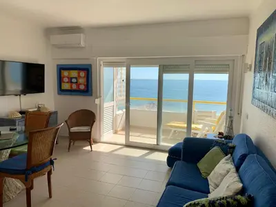a living room with a blue couch and a view of the ocean at Apartamento Frente praia in Quarteira