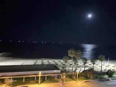a view of the beach at night with the moon at Apartamento Frente praia in Quarteira