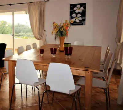 a dining room table with white chairs and a vase with flowers at Villa Núria in Loulé