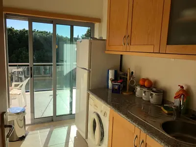 a kitchen with a sink and a refrigerator and a balcony at Pinetops holidays Apartment in Albufeira