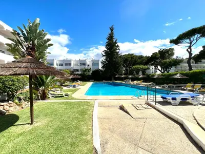 a swimming pool with an umbrella next to a resort at Sea Gardens - Alvaflor - Vilamoura in Vilamoura