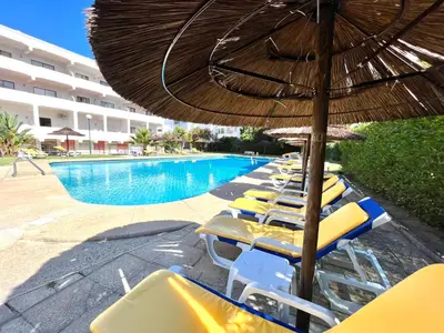 a group of chairs and umbrellas next to a swimming pool at Sea Gardens - Alvaflor - Vilamoura in Vilamoura