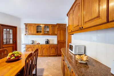 a kitchen with wooden cabinets and a table with a bowl of fruit at Villa Grace Bay by Algarve Vacation in Guia
