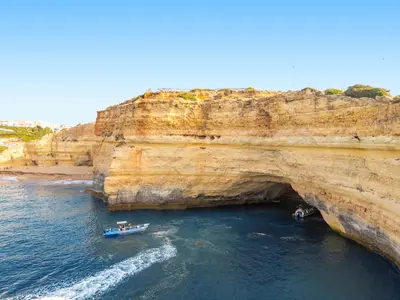 two boats in the water next to a large cliff at Villa Grace Bay by Algarve Vacation in Guia