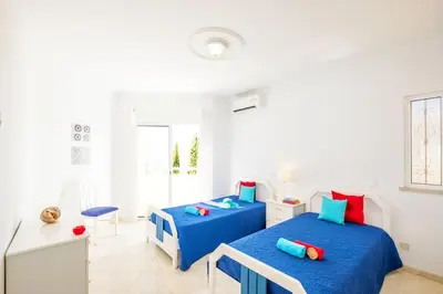 two beds in a white room with blue and red pillows at Villa Grace Bay by Algarve Vacation in Guia