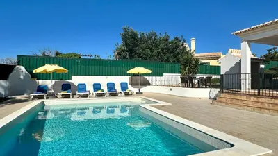 a swimming pool with chairs and umbrellas in a yard at Abby by Check-in Portugal in Albufeira