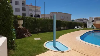 a blue pole in the grass next to a swimming pool at Alta Oura Prime by Sunny Deluxe in Albufeira