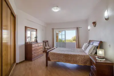 a bedroom with a bed and a dresser and a window at Villa do Lago in Albufeira