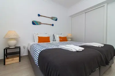 a white bedroom with a bed with orange pillows at Blue Apartment Balaia Space - By Dalma Portuguesa in Albufeira