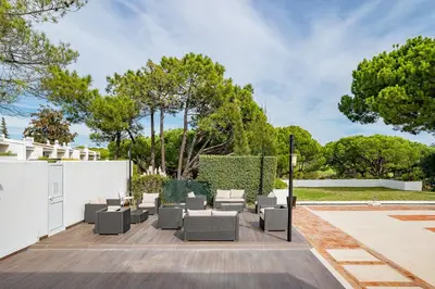 a patio with chairs and a fence and trees at Apartment Victoria - Quinta do Lago in Quinta do Lago
