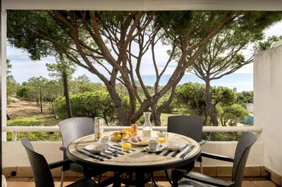 a table and chairs on a balcony with a tree at Apartment Victoria - Quinta do Lago in Quinta do Lago