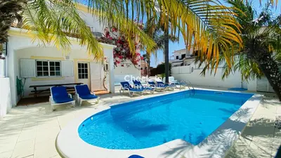 a swimming pool with blue chairs next to a building at Rafael by Check-in Portugal in Albufeira