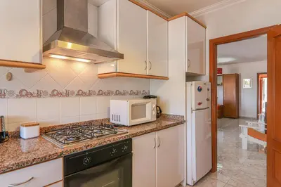a kitchen with a stove top oven next to a microwave at Casa do Algarve in Albufeira