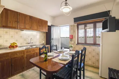 a kitchen with a wooden table and a refrigerator at Casa Guerreiro in Branqueira