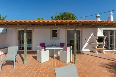 a patio with a table and chairs on a brick patio at Casa Mimao in Albufeira