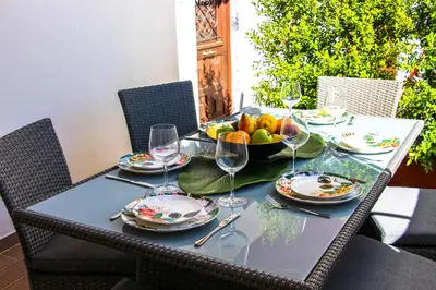 a table with a bowl of fruit and wine glasses at Apartamentos SweetHomes in Faro