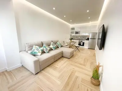 a living room with a white couch and a kitchen at Apartamentos SweetHomes in Faro