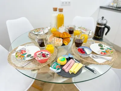 a glass table topped with plates of food and drinks at Apartamentos SweetHomes in Faro