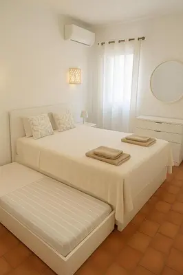 a white bedroom with two beds and a mirror at Oura Family House in Albufeira