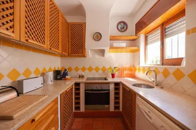 a kitchen with wooden cabinets and a sink at Oura Family House in Albufeira