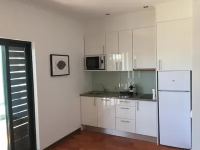 a kitchen with white cabinets and a white refrigerator at Tossan House in Vilamoura Downtown in Quarteira