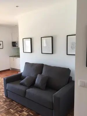 a blue couch in a living room with pictures on the wall at Tossan House in Vilamoura Downtown in Quarteira