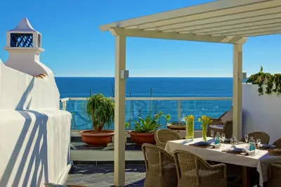 a patio with tables and chairs and a view of the ocean at Casa Latino - Oceanfront - Luxury & Charming villa- Jacuzzi at Rooftop by DreamvillasAlbufeira in Albufeira