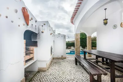 a patio with a wooden bench and a swimming pool at Oura Villa V3 com Piscina Privada in Albufeira
