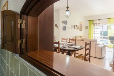 a dining room and living room with a table and chairs at Oura Villa V3 com Piscina Privada in Albufeira