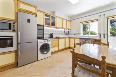 a kitchen with a table and a washer and dryer at Villa Moises in Albufeira